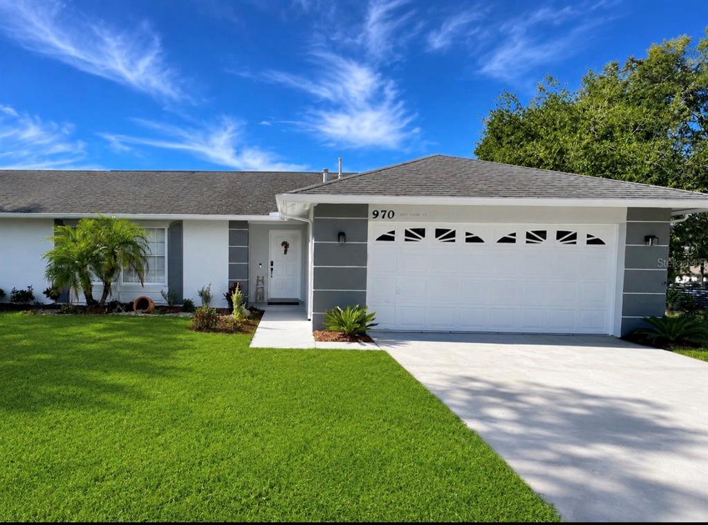 A single-story house with a white garage door, gray accents, and a green lawn — 970 AMY RIDGE COURT, KISSIMMEE, FL