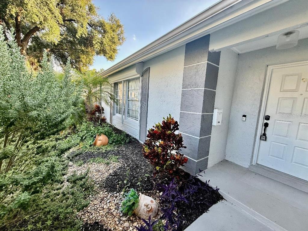 A light blue house exterior features a white front door and a landscaped garden bed — 970 AMY RIDGE COURT, KISSIMMEE, FL
