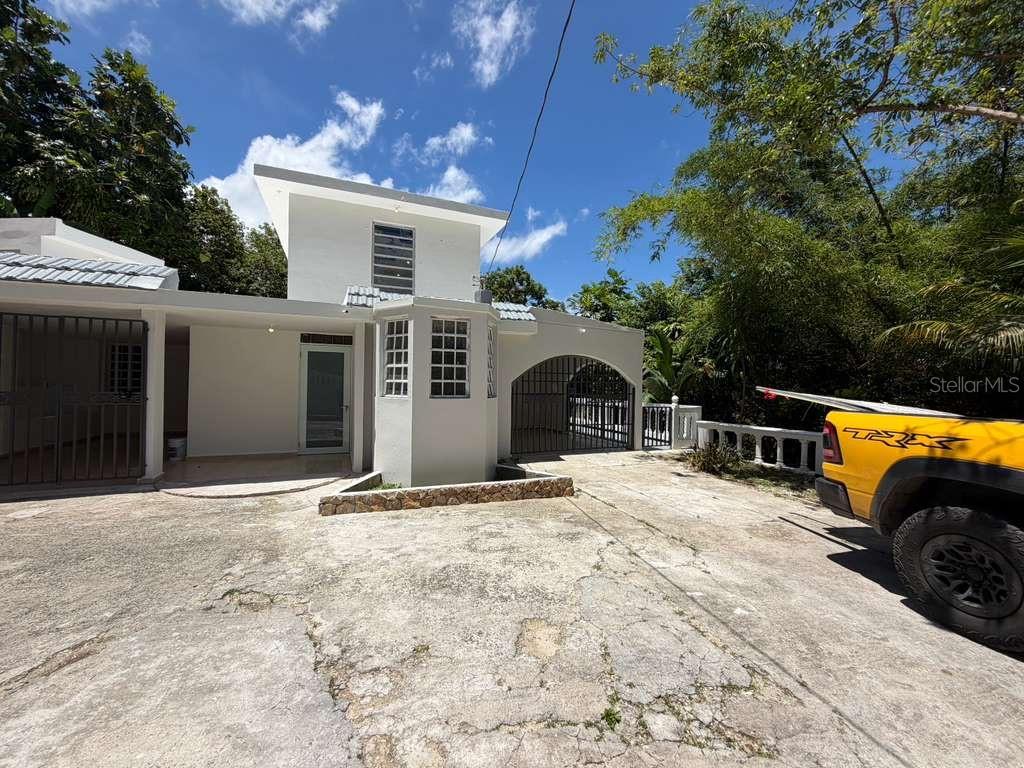 A white two-story house with a concrete driveway and a yellow truck parked outside — 8 Martorell MARTORELL, YABUCOA, PR