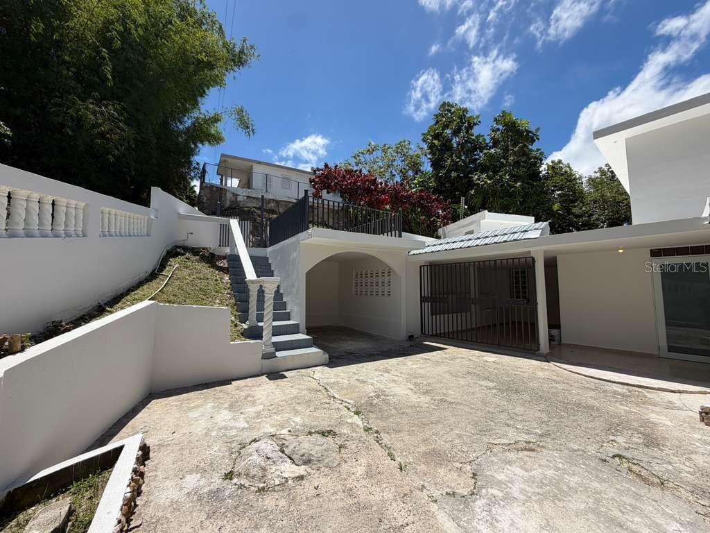 A concrete driveway leads to a covered carport, a gated patio, and stairs to a terrace — 8 Martorell MARTORELL, YABUCOA, PR