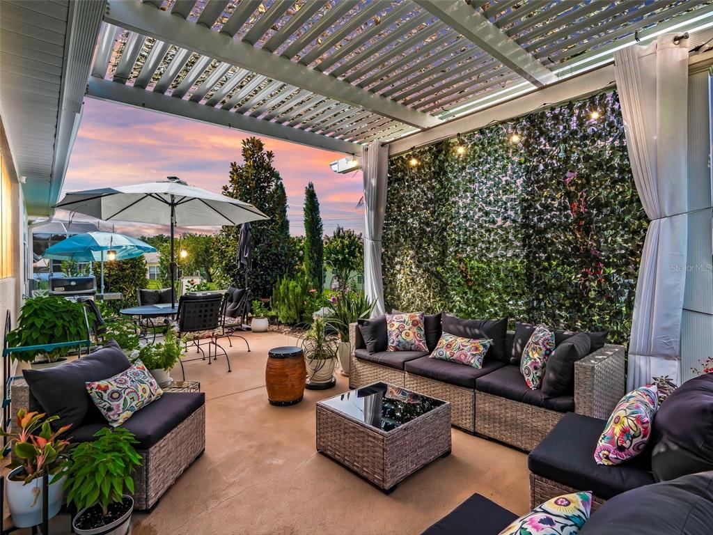 A covered patio features wicker outdoor furniture, a green privacy wall, and a sunset view — 11860 SE 179TH STREET, SUMMERFIELD, FL