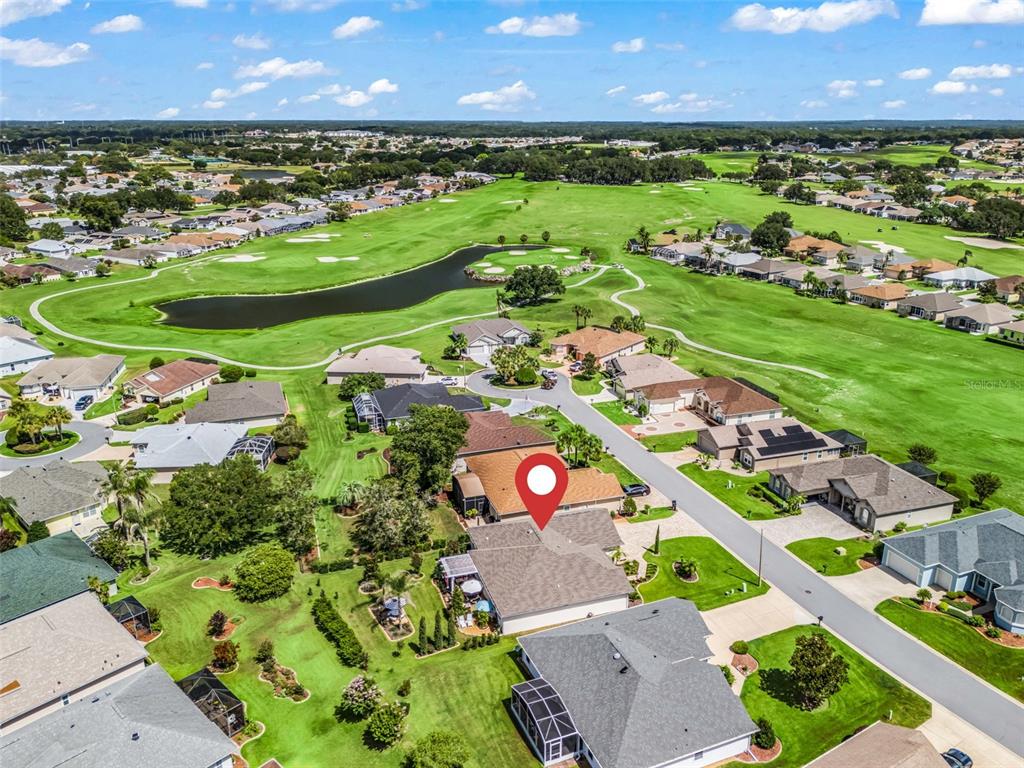 An aerial view shows a residential neighborhood with houses surrounding a golf course and pond — 11860 SE 179TH STREET, SUMMERFIELD, FL