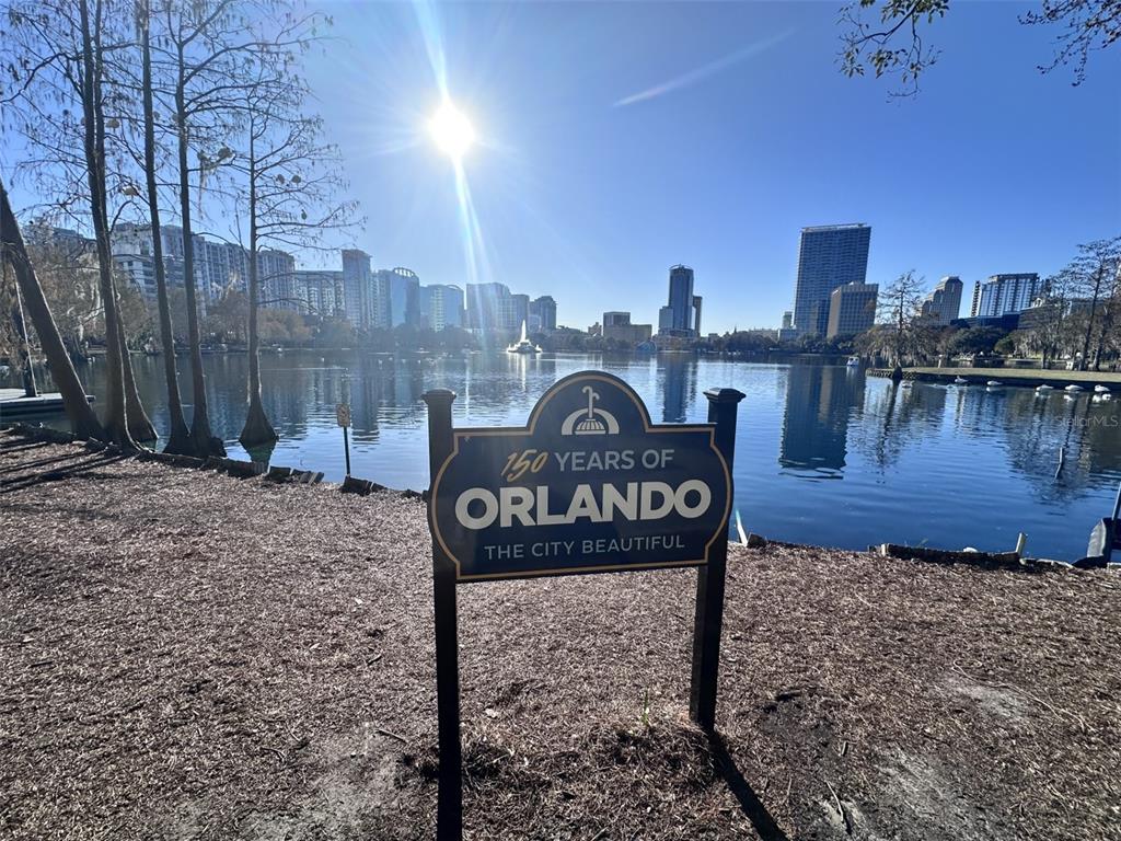 A sign commemorating 150 years of Orlando stands before a lake and city skyline — 155 S COURT AVENUE UNIT 1911, ORLANDO, FL