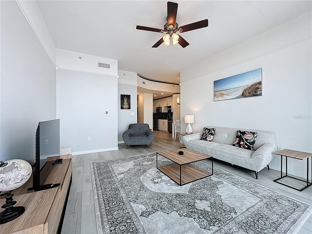 A living room features a grey sofa, a patterned area rug, and a ceiling fan — 155 S COURT AVENUE UNIT 1911, ORLANDO, FL