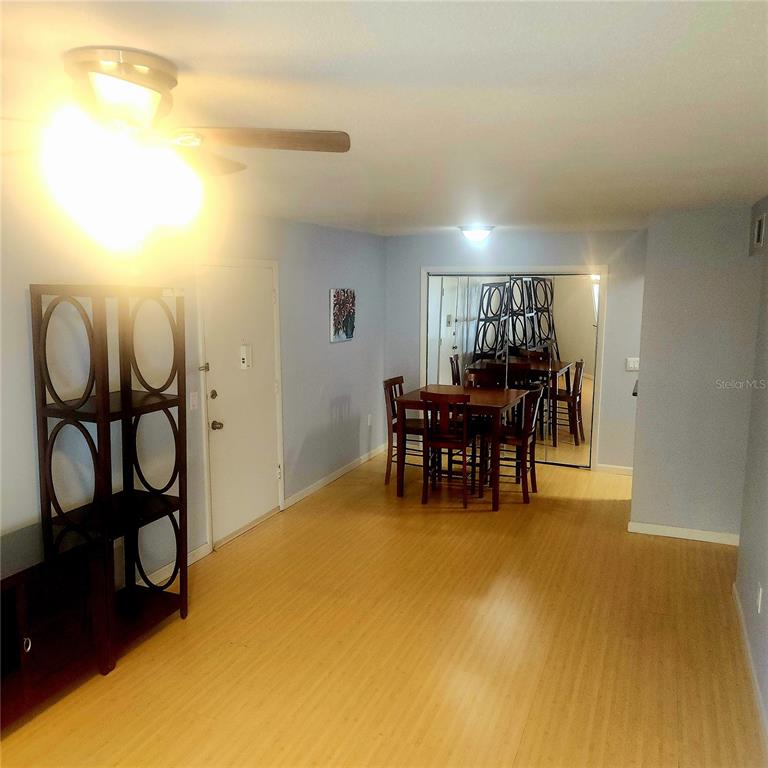 A dining area features light wood flooring, a ceiling fan, and a mirrored closet wall — 1700 SW 16TH COURT UNIT P28, GAINESVILLE, FL