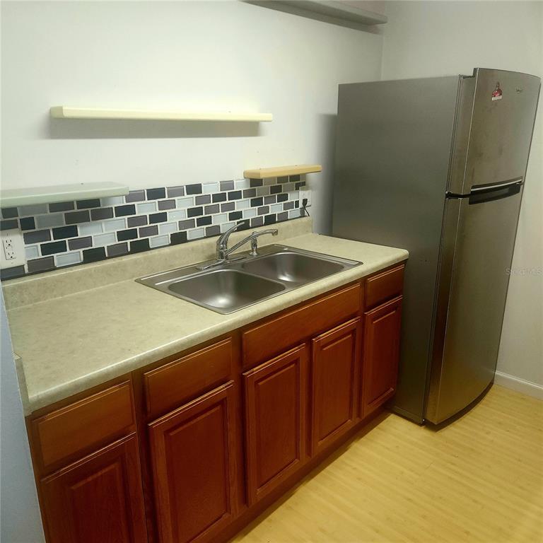 A kitchen features wood cabinets, a stainless steel sink, and a stainless steel refrigerator — 1700 SW 16TH COURT UNIT P28, GAINESVILLE, FL