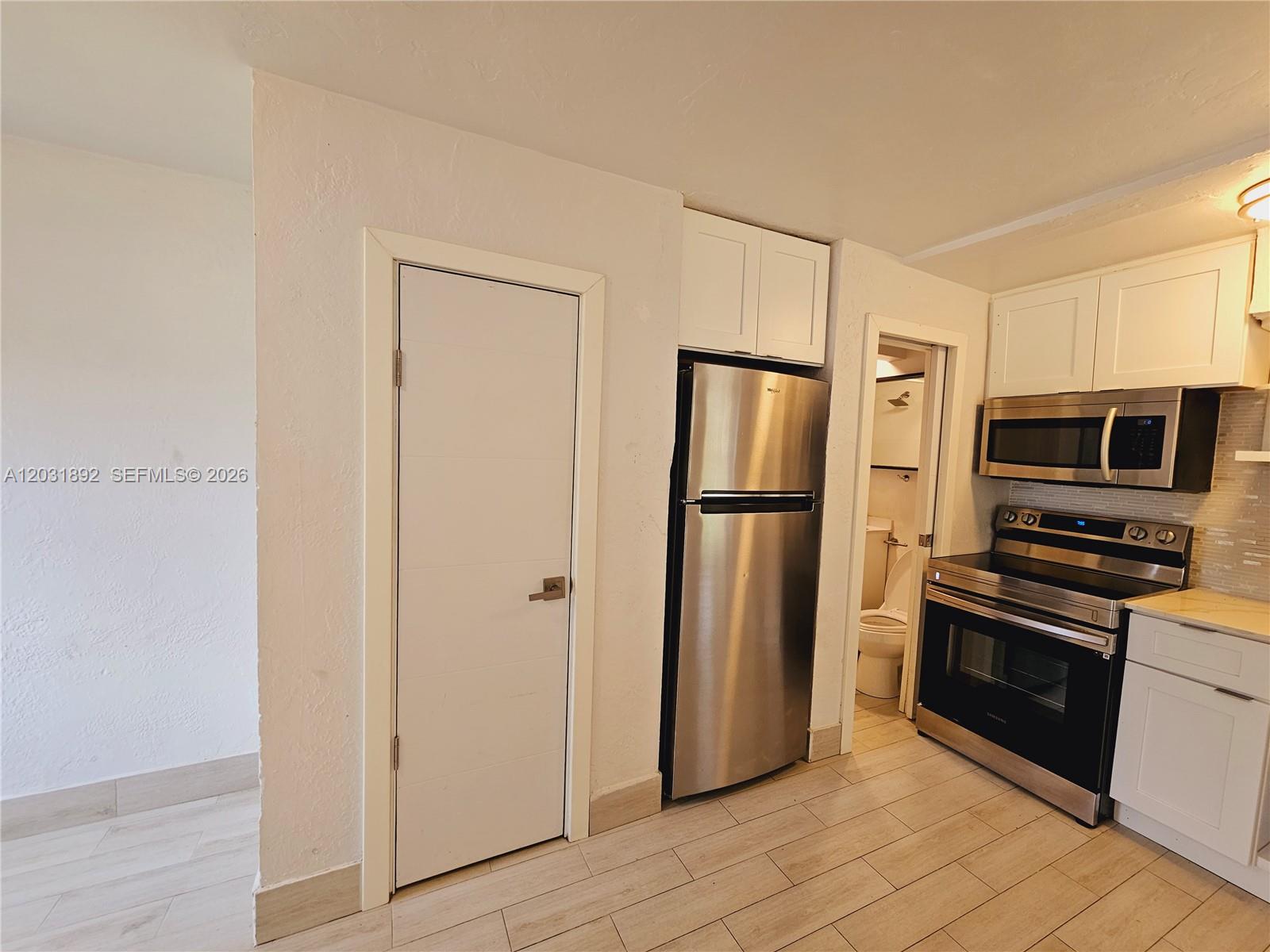 A kitchen features stainless steel appliances, white cabinetry, and light-colored tile flooring — 26 SE 13th Ter # 6, Dania Beach FL 33004, DANIA BEACH, FL