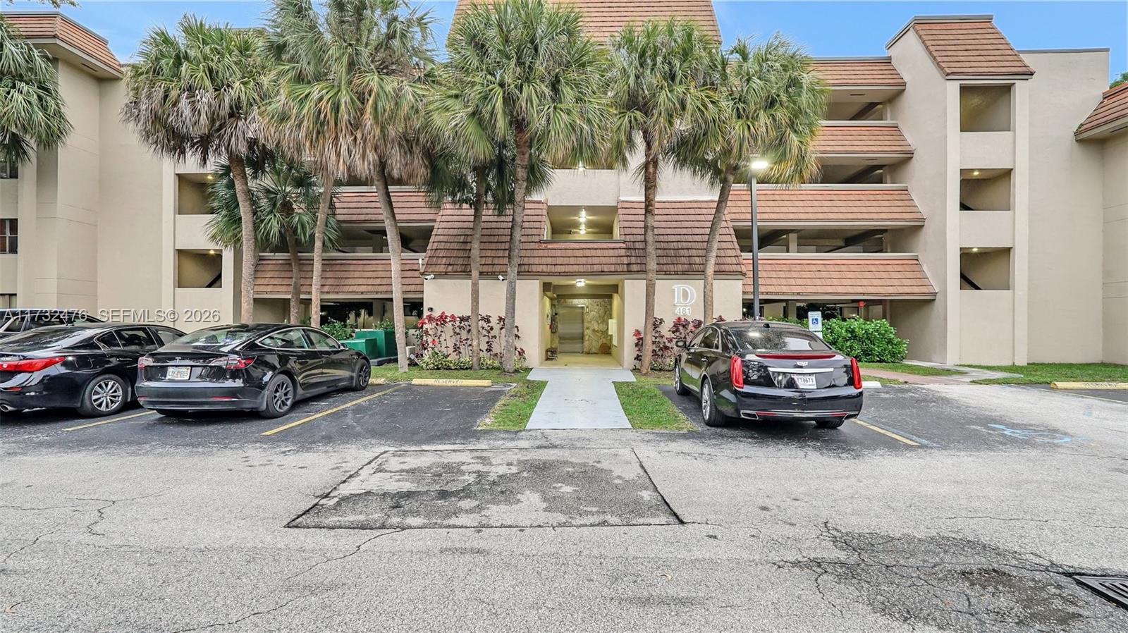The exterior of a multi-story apartment building features palm trees and a parking lot — 481 Ives Dairy Rd # 4, Miami FL 33179, MIAMI, FL