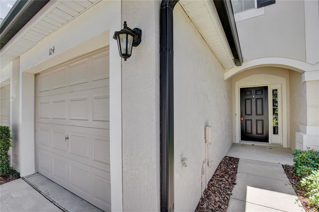 A beige garage with a black lantern light and a black front door — 6080 TWAIN STREET UNIT 104, ORLANDO, FL