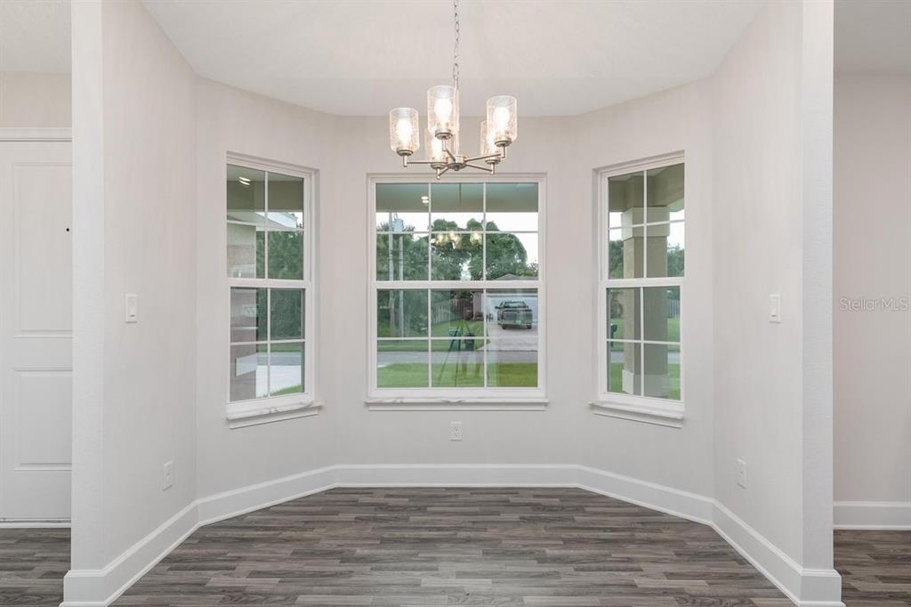 A dining nook with a chandelier, three windows, and wood-look flooring — 53 SLEEPY HOLLOW TRAIL, PALM COAST, FL