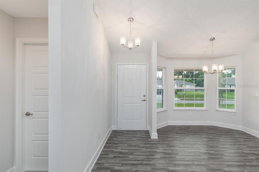 An entryway with gray wood-look flooring leads to a dining area with a bay window — 53 SLEEPY HOLLOW TRAIL, PALM COAST, FL