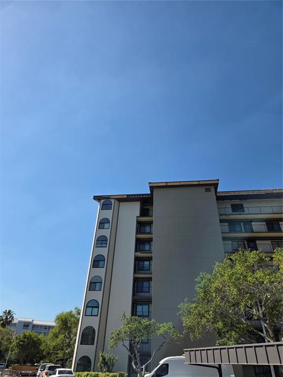 A low-angle exterior view of a multi-story apartment building with a white van parked below — 650 ISLAND WAY UNIT 202, CLEARWATER BEACH, FL