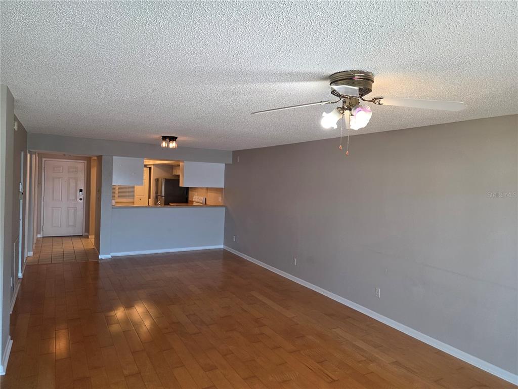A living room with hardwood floors, a ceiling fan, and an open kitchen pass-through — 650 ISLAND WAY UNIT 202, CLEARWATER BEACH, FL