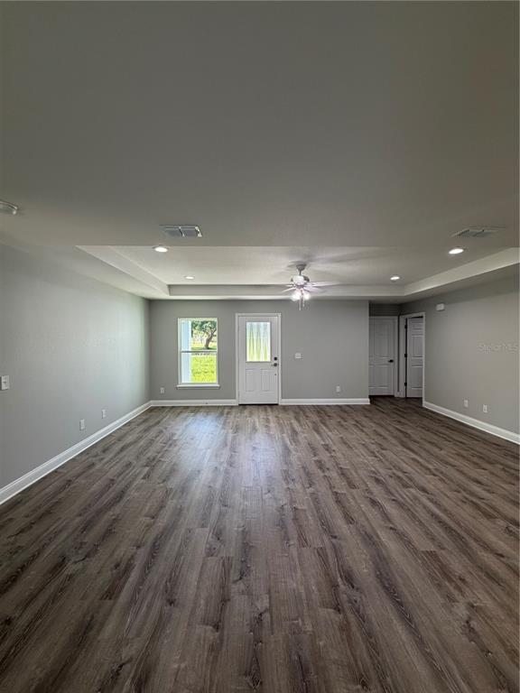 A spacious living room features light gray walls, wood-look flooring, and a tray ceiling — 1987 LEMON DRIVE, LAKE WALES, FL