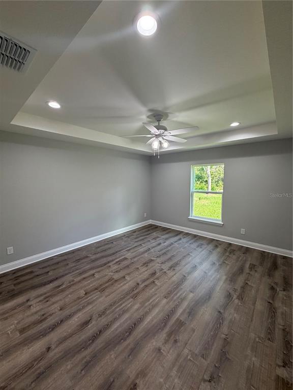 A bedroom with gray walls, wood-look flooring, and a tray ceiling with a fan — 1987 LEMON DRIVE, LAKE WALES, FL