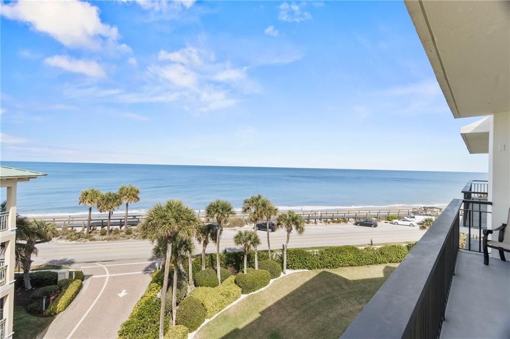 An elevated view from a balcony overlooking a road, palm trees, and the ocean — 4101 Ocean Drive, Vero Beach FL 32963, VERO BEACH, FL