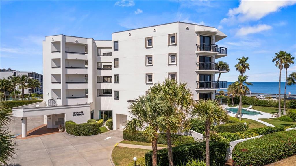 An exterior view of a multi-story white apartment building with balconies and a swimming pool — 4101 Ocean Drive, Vero Beach FL 32963, VERO BEACH, FL