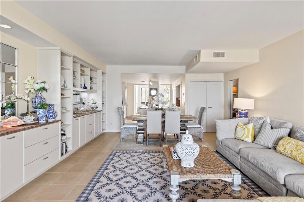 A living room with a built-in cabinet, dining area, and neutral furniture on a patterned rug — 4101 Ocean Drive, Vero Beach FL 32963, VERO BEACH, FL