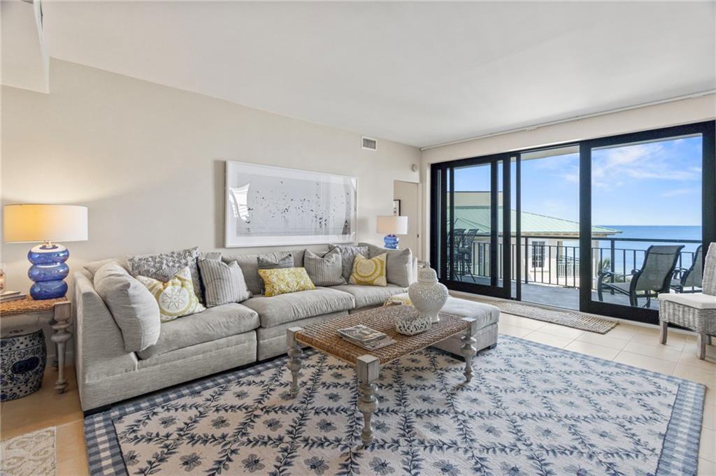 A living room features a large sectional sofa, patterned area rug, and sliding glass balcony doors — 4101 Ocean Drive, Vero Beach FL 32963, VERO BEACH, FL