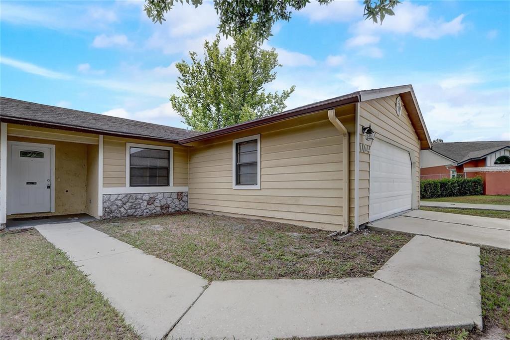 A single-story house with tan horizontal siding, a stone facade accent, and a white garage — 104 TURIN WAY, KISSIMMEE, FL