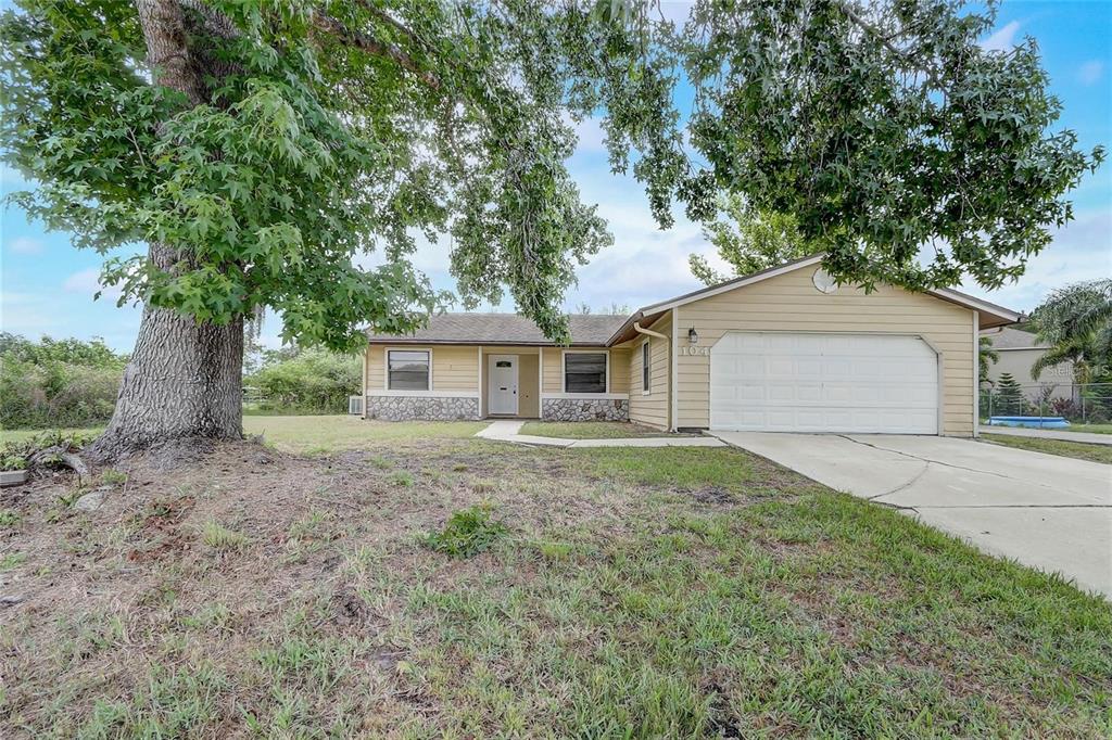 A single-story house with tan siding, a stone facade, and a two-car garage — 104 TURIN WAY, KISSIMMEE, FL