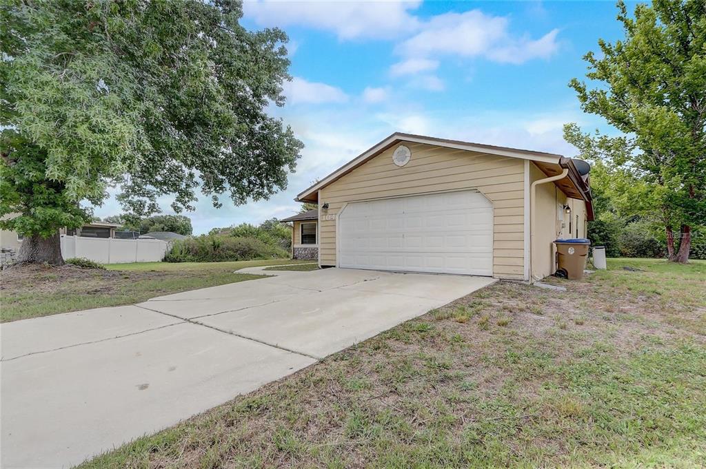 A beige house with a white garage door and a concrete driveway sits on grass — 104 TURIN WAY, KISSIMMEE, FL