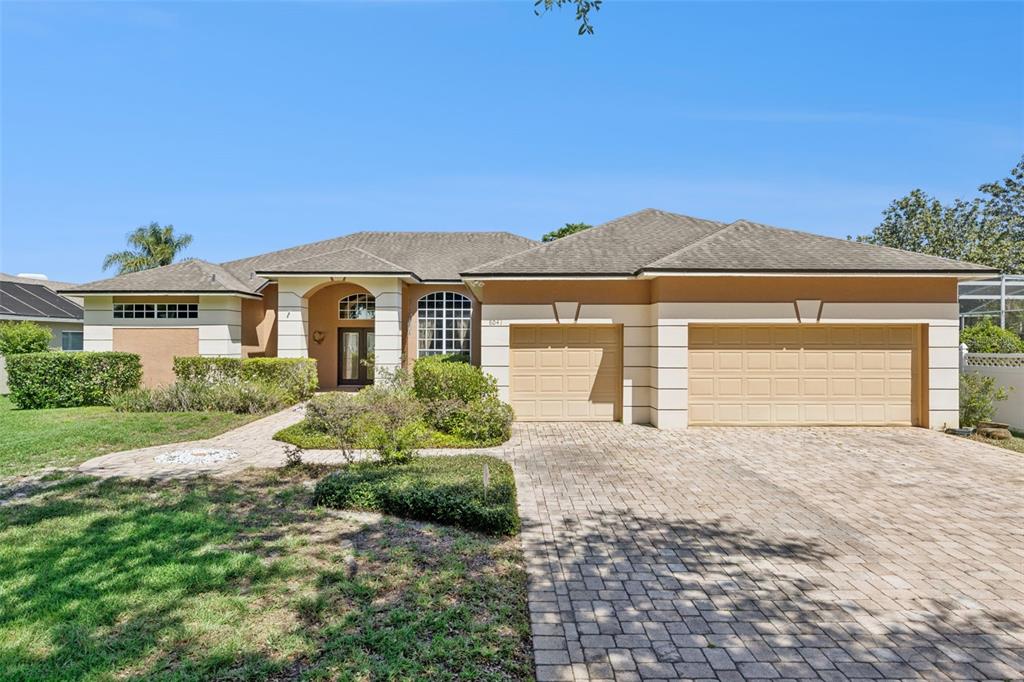 A single-story house with a tan stucco exterior, a paver driveway, and a three-car garage — 8041 MONIER WAY, ORLANDO, FL