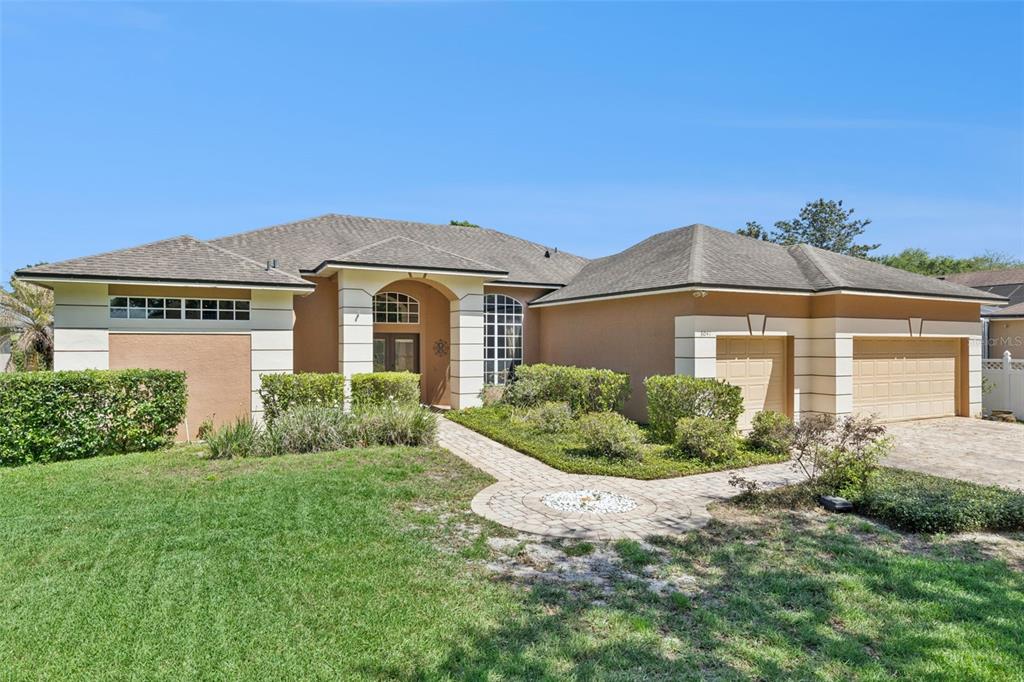 A single-story house with a tan stucco exterior, a paver walkway, and a two-car garage — 8041 MONIER WAY, ORLANDO, FL
