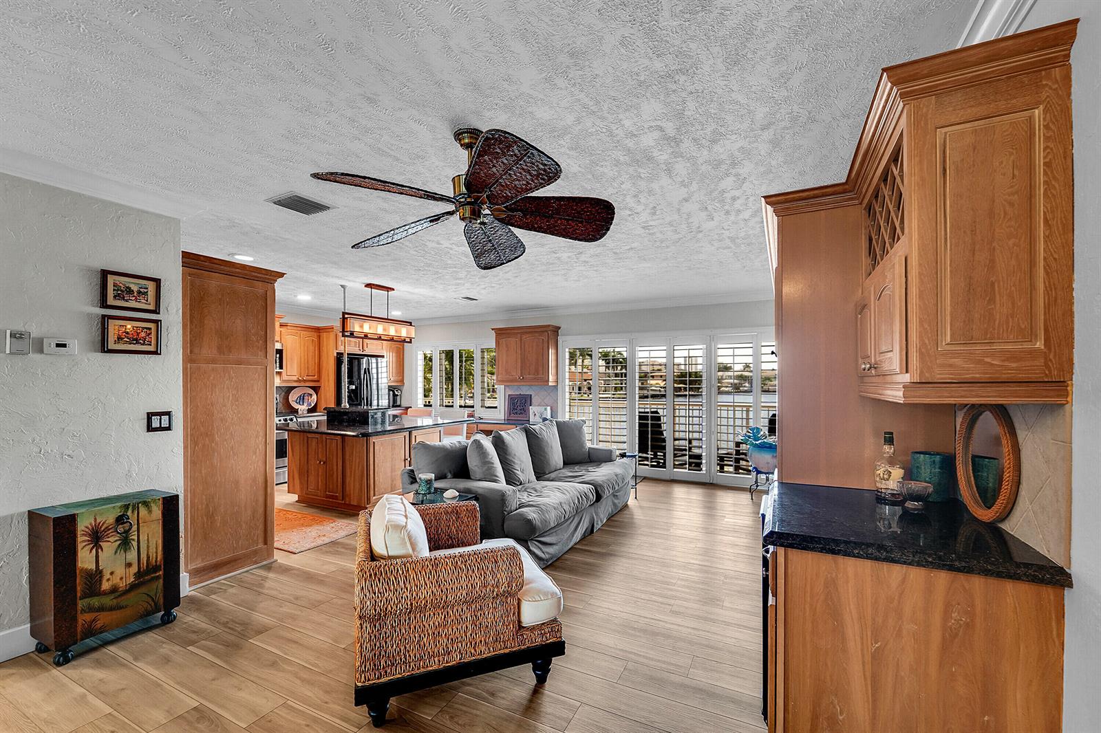 An open-concept living room and kitchen feature wood cabinets, a ceiling fan, and sliding doors — 1201 S Riverside Drive # 201, Pompano Beach FL 33062, POMPANO BEACH, FL