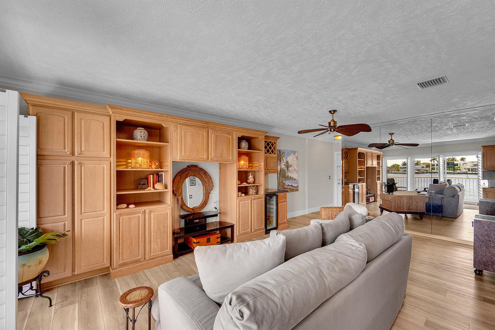 A living room features light wood built-in cabinetry, a gray sofa, and a mirrored wall — 1201 S Riverside Drive # 201, Pompano Beach FL 33062, POMPANO BEACH, FL