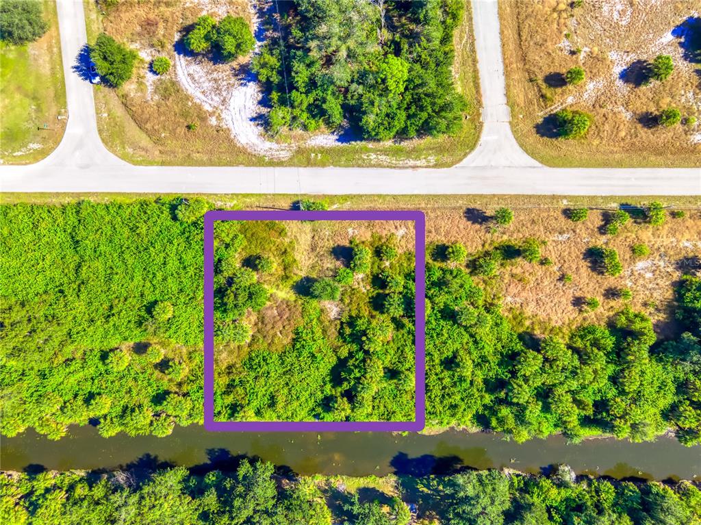 An aerial view shows a rectangular plot of land outlined in purple near a canal — 163 SANTA MARTA STREET, PORT CHARLOTTE, FL