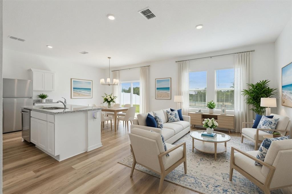 An open-concept living and dining area with a kitchen island, light wood floors, and windows — 8700 SPORTSMAN LOOP, GROVELAND, FL