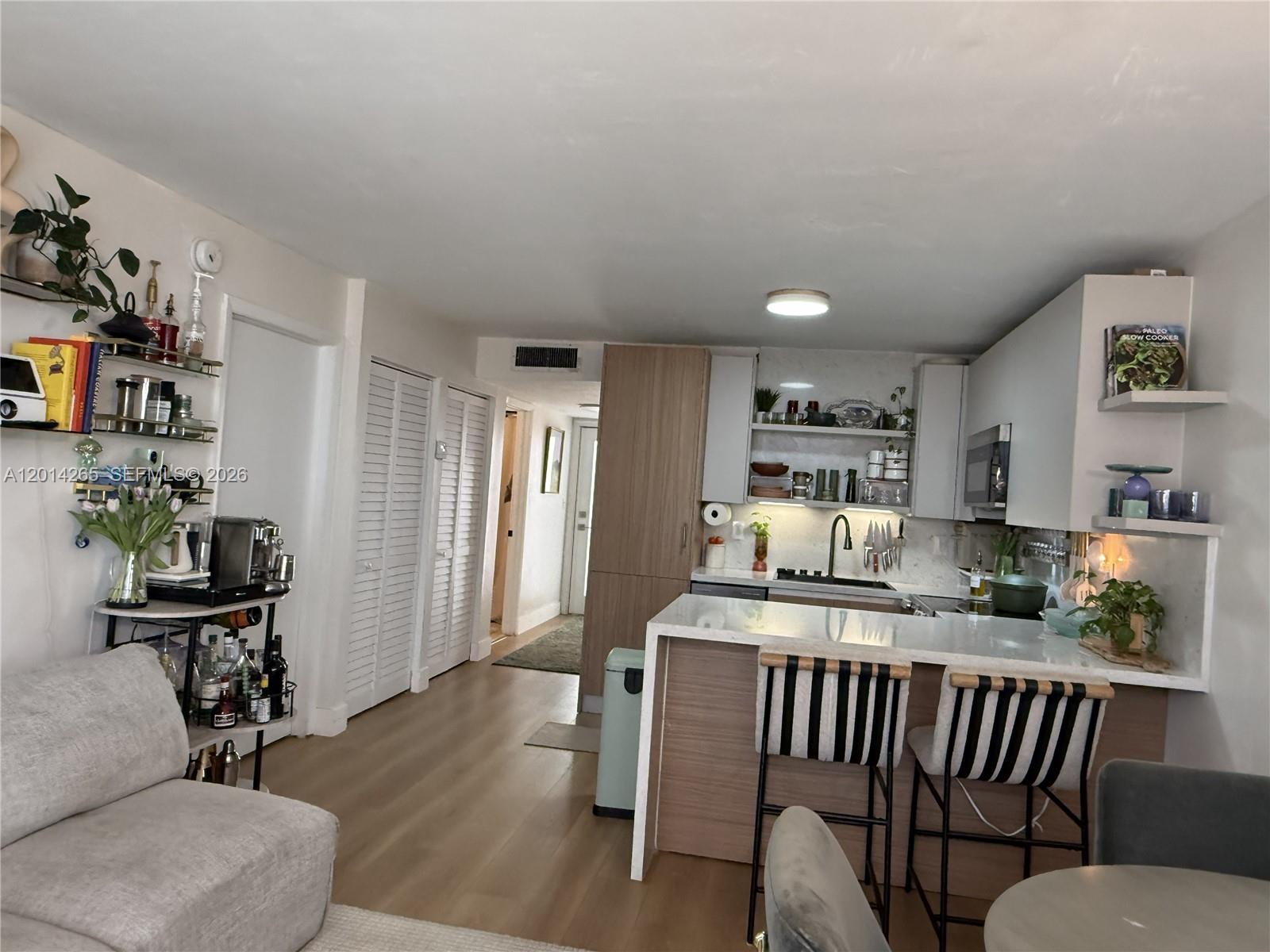 A kitchen with light wood cabinetry, white countertops, and a breakfast bar with striped stools — 1666 West Ave # 305, Miami Beach FL 33139, MIAMI BEACH, FL