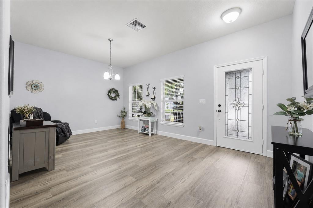 A bright room with light wood-look flooring, a glass-paneled front door, and a dining chandelier — 2814 MAPLE BROOK LOOP, LUTZ, FL