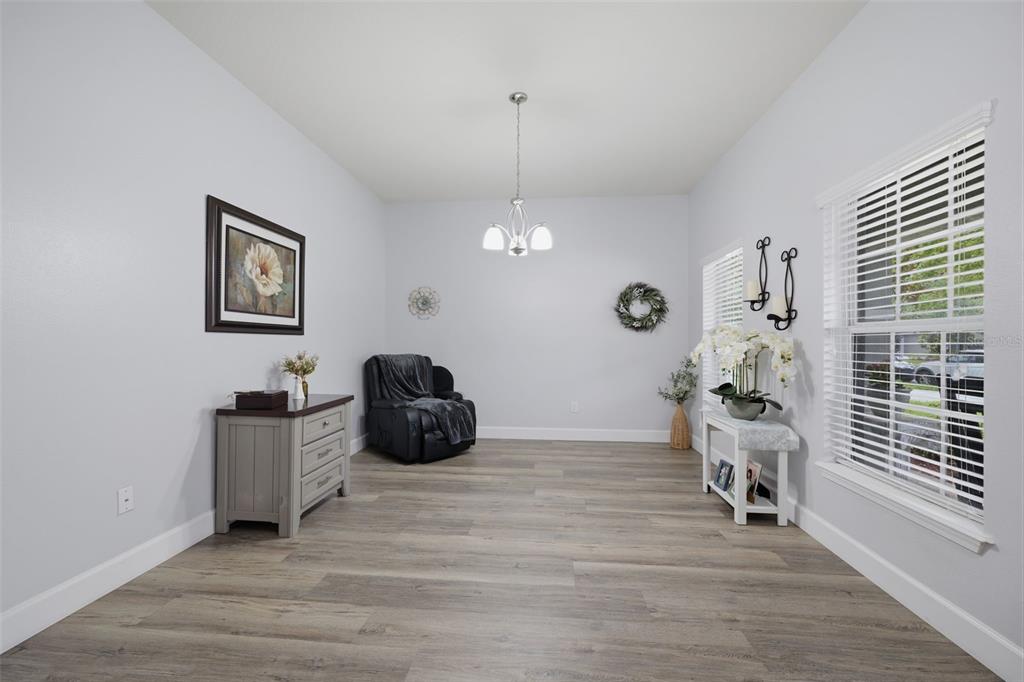 A dining room with light gray walls, wood-look flooring, a chandelier, and a window — 2814 MAPLE BROOK LOOP, LUTZ, FL