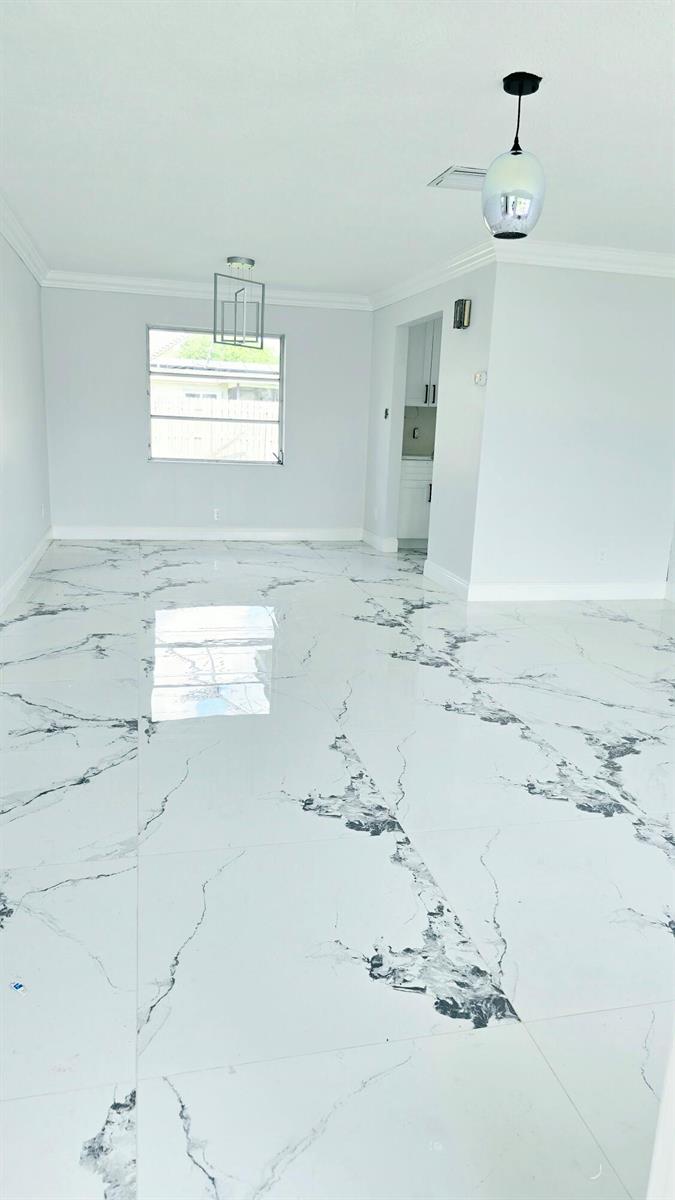 An empty room features white marble-look tile flooring, light gray walls, and two hanging light fixtures — LAUDERHILL, FL