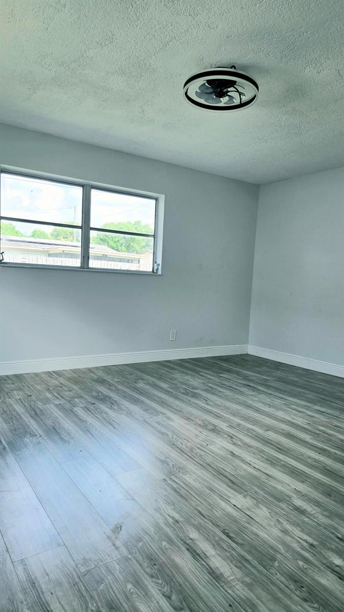 An empty room features gray wood-look flooring, light gray walls, and a modern ceiling fan — LAUDERHILL, FL