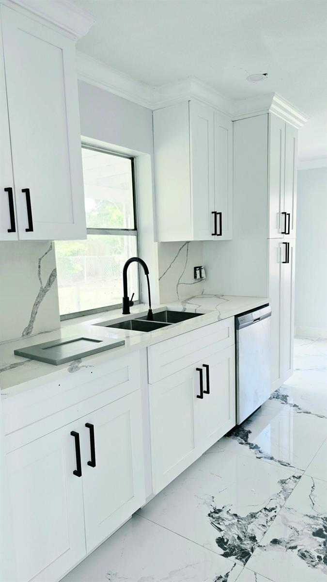 A kitchen features white shaker cabinets, marble-style countertops, a black faucet, and white tiled floors — LAUDERHILL, FL