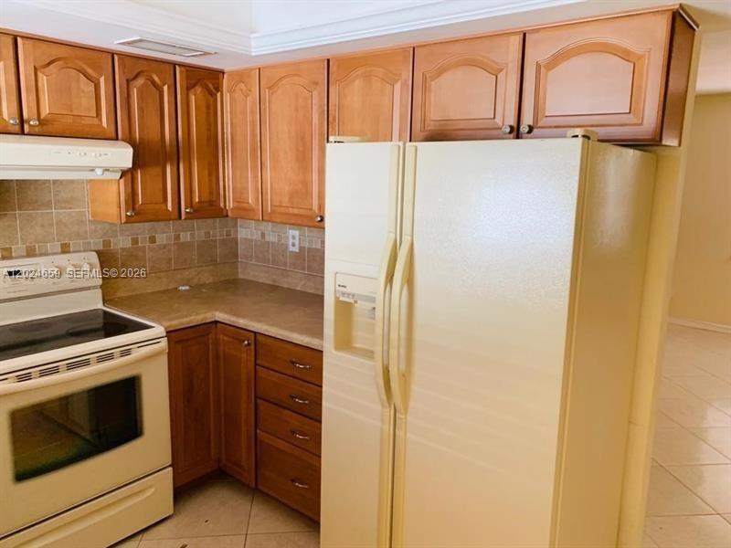 A kitchen features wood cabinets, a white stove, and a white side-by-side refrigerator — 344 SW 1st St # 9, Pompano Beach FL 33060, POMPANO BEACH, FL