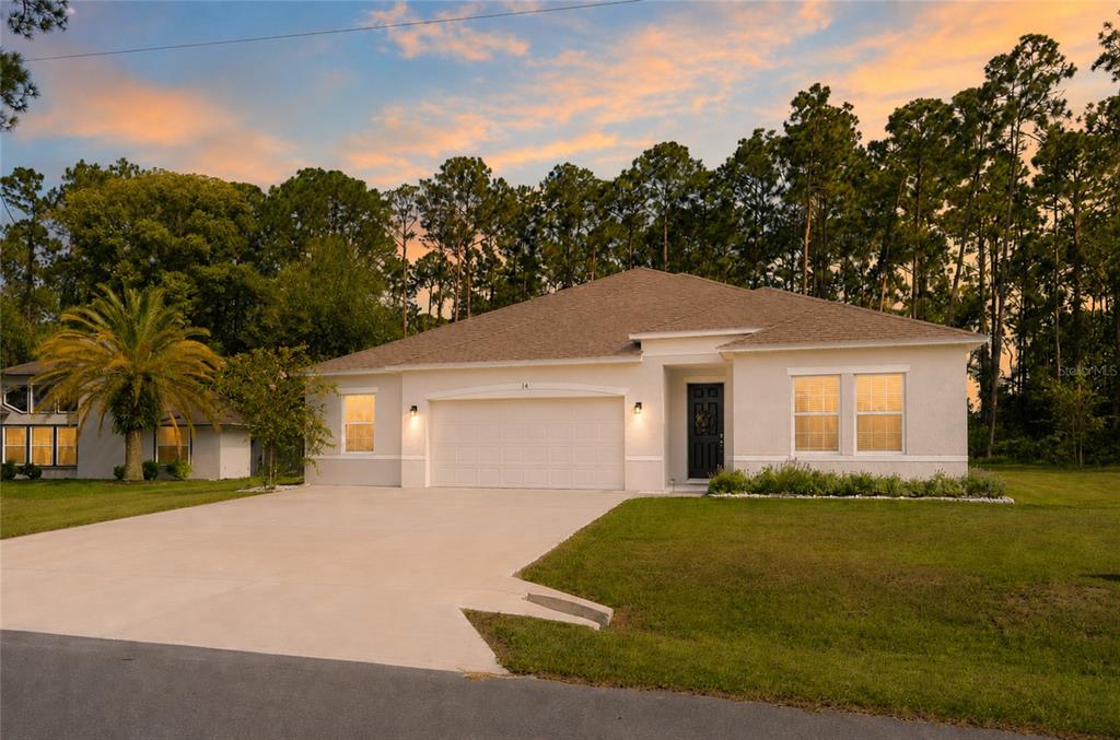 A single-story house with a white stucco exterior, a two-car garage, and a concrete driveway — 14 WOODWORTH DRIVE, PALM COAST, FL