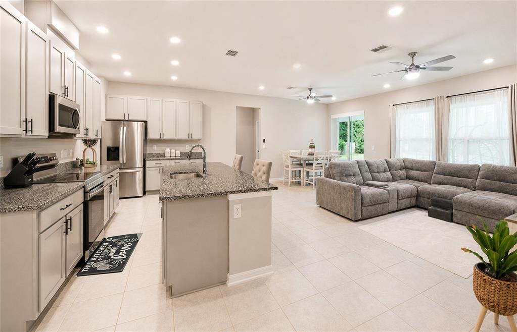 An open-concept kitchen with granite countertops and light cabinetry flows into a living area — 14 WOODWORTH DRIVE, PALM COAST, FL