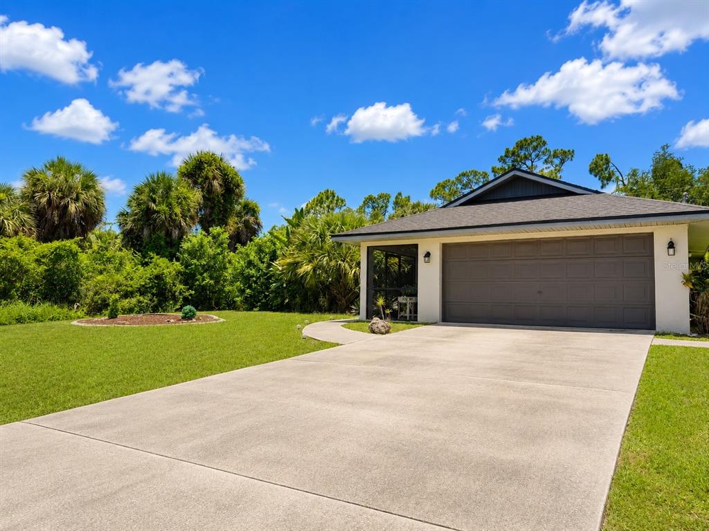 A single-story house with a gray garage door and a screened porch under a blue sky — 307 BARGER DRIVE, PORT CHARLOTTE, FL