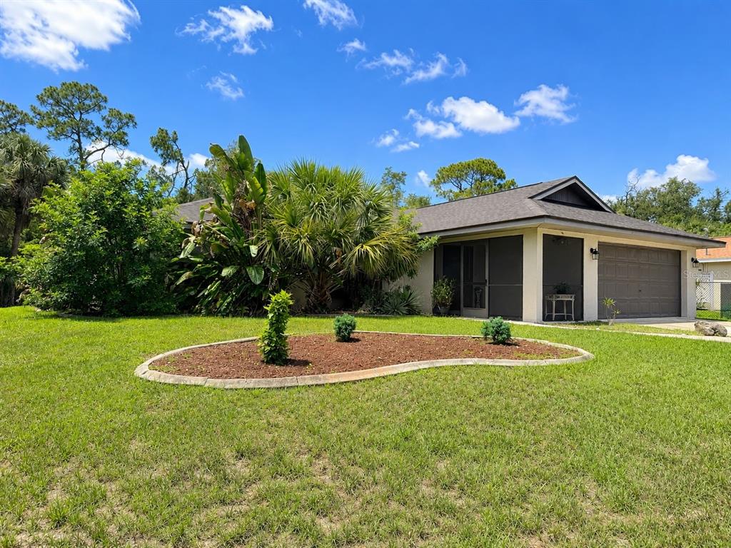 A single-story house with a two-car garage and a landscaped front yard — 307 BARGER DRIVE, PORT CHARLOTTE, FL