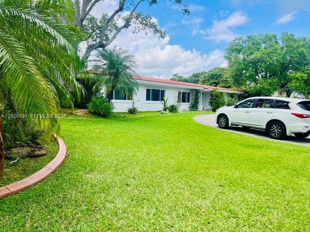 A white single-story house with a green lawn and a white SUV parked outside — 7910 SW 73rd Ct, Miami FL 33143, MIAMI, FL