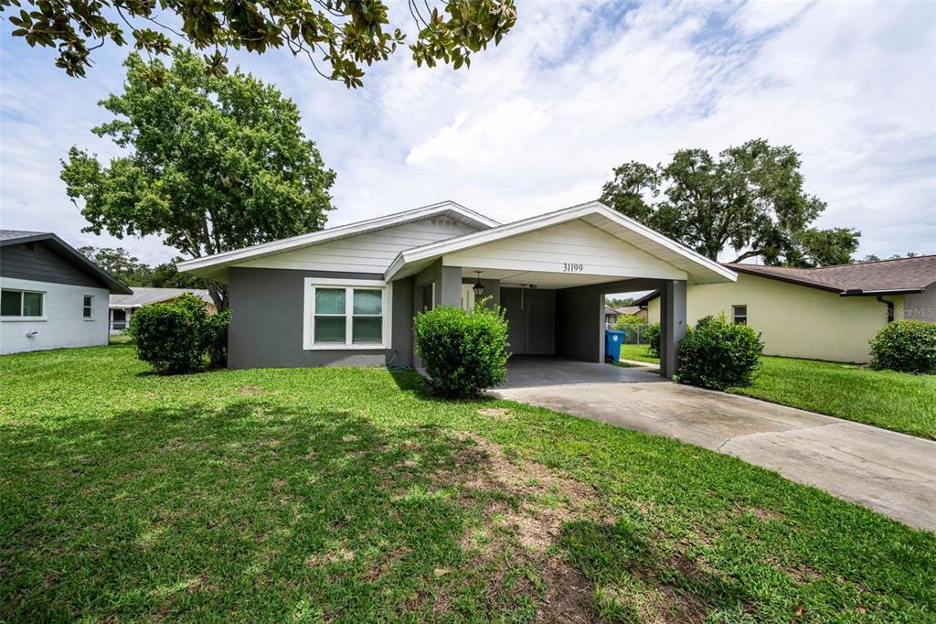 A single-story house with a gray exterior, white trim, and an attached carport — 31199 LANCEWOOD DRIVE, BROOKSVILLE, FL