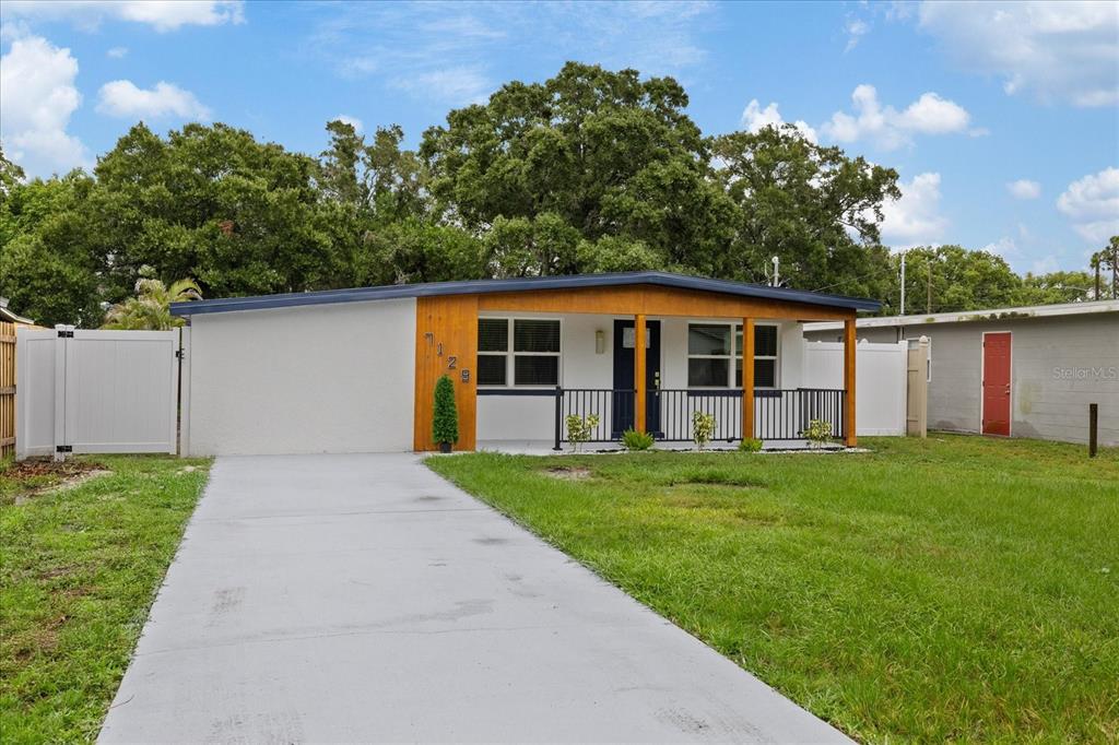 A single-story house with a white exterior, wood-paneled accent wall, and a concrete driveway — 7129 63RD STREET N, PINELLAS PARK, FL