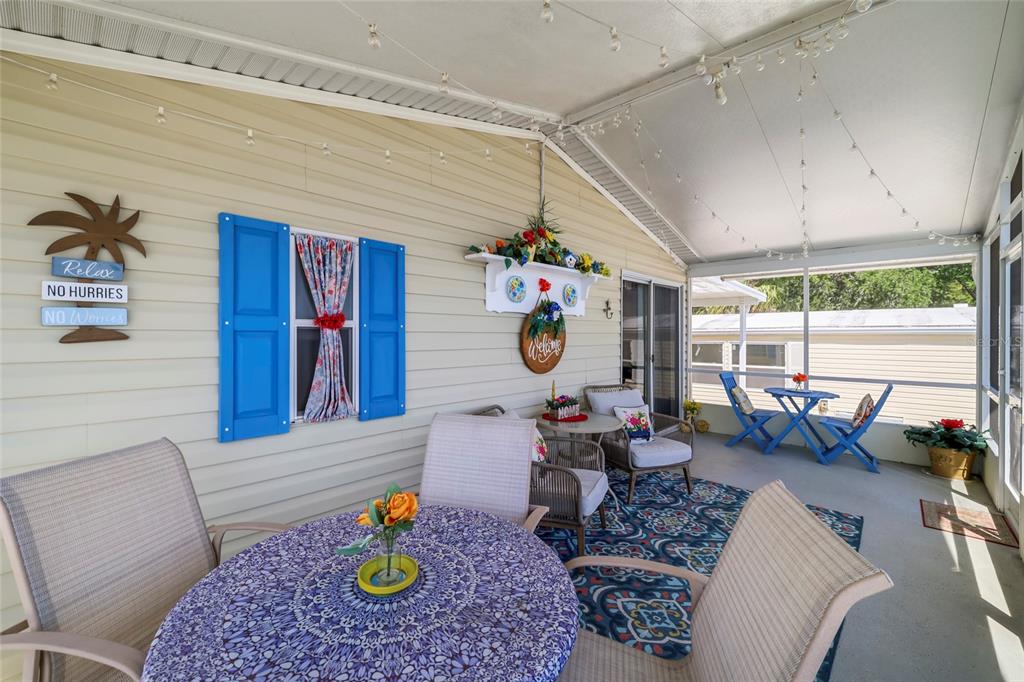 A screened-in porch features a dining set, patterned area rug, and blue decorative shutters — 2927 COQUINA ESPLANADE, PUNTA GORDA, FL