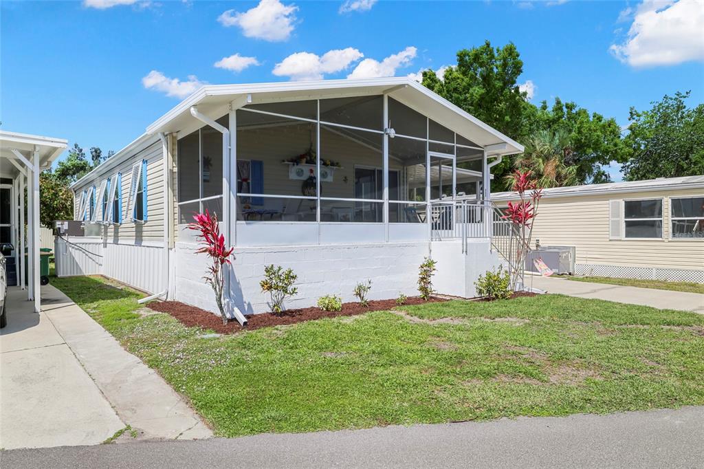 A mobile home with a white screened-in front porch and a concrete driveway — 2927 COQUINA ESPLANADE, PUNTA GORDA, FL