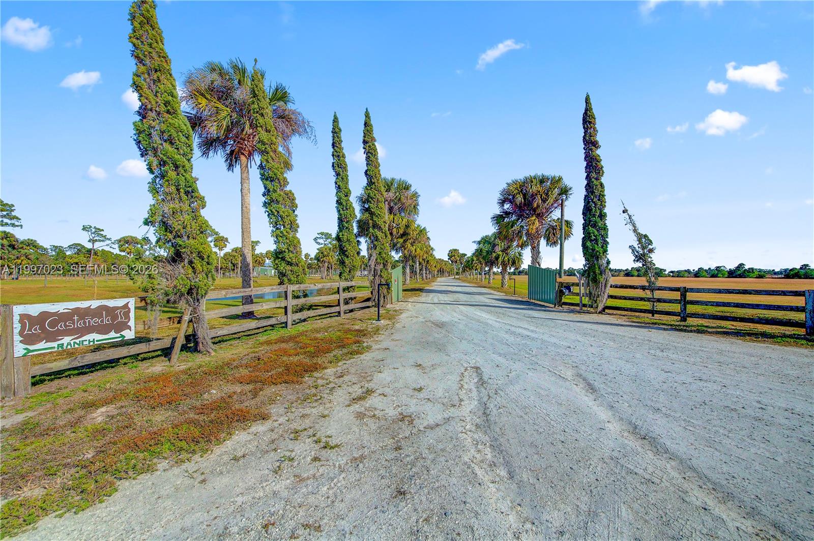 A dirt driveway leads through a gated entrance at La Castañeda Ranch — 30003 SW Martin Hwy, Okeechobee FL 34974, OKEECHOBEE, FL