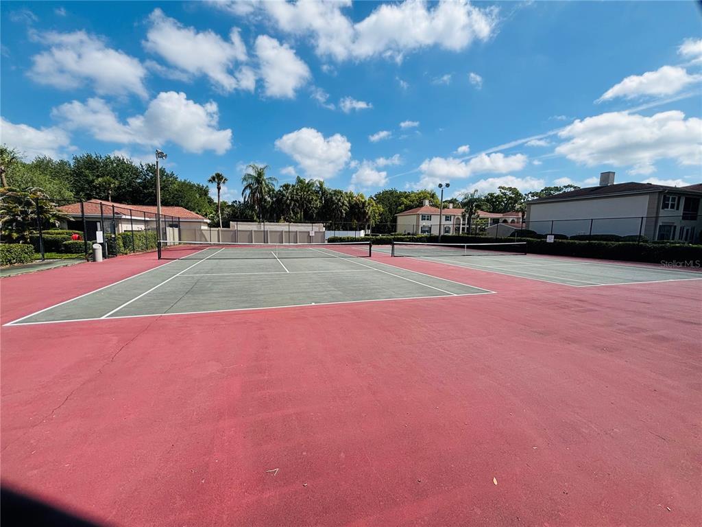 Two outdoor tennis courts with red and green surfaces under a blue sky — 10356 CARROLLWOOD LANE UNIT 205, TAMPA, FL